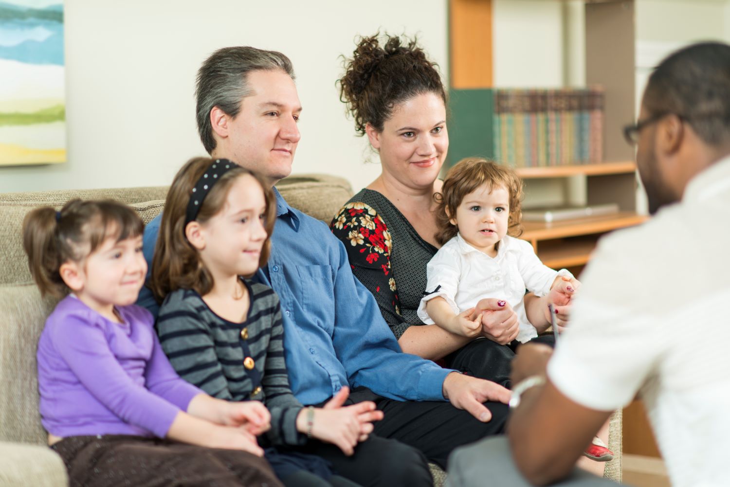 Padre y madre con sus tres hijos hablando con un miembro del personal de Head Start.