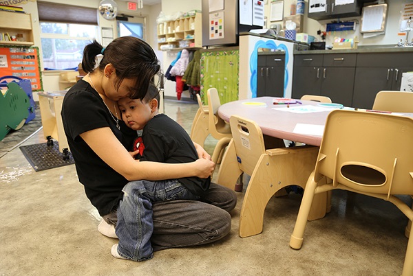 Maestra abrazando a un niño perturbado en el aula.