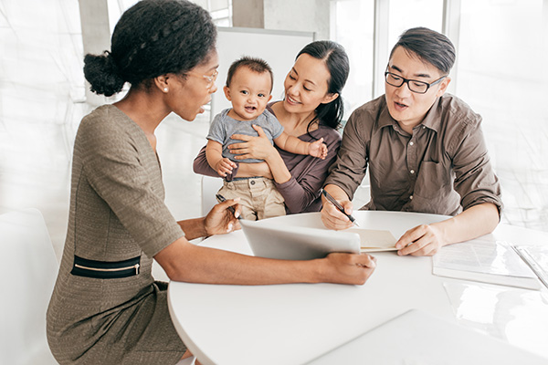 Family with a child, talking with a consultant and filling paperwork.