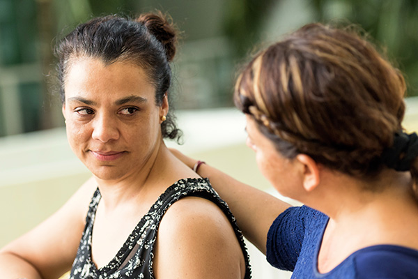 Woman talking to another while placing an hand on her back.