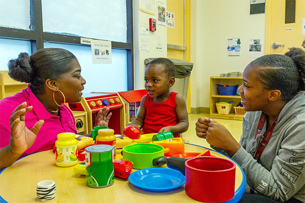 Teacher talking with a mother and her child in the classroom.