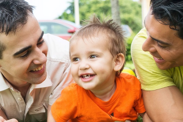 Padres sosteniendo a un niño y sonriéndole.