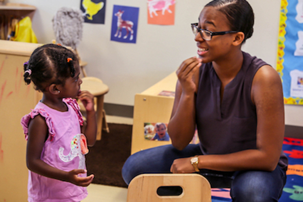 Teacher talking with preschooler using American Sign Language.