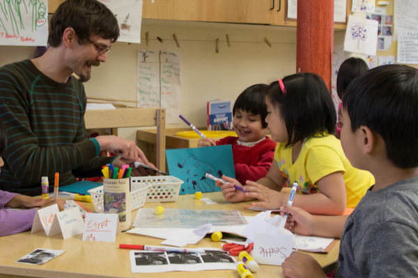 Preschool age children working on a craft project with their teacher.