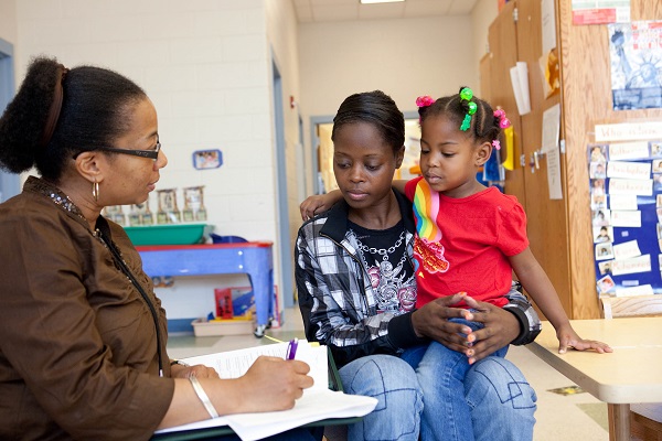 Mother and child meeting with an evaluator in a classroom.