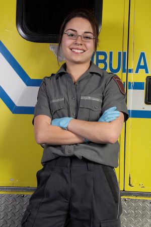 A female EMS worker standing in front of an ambulance.