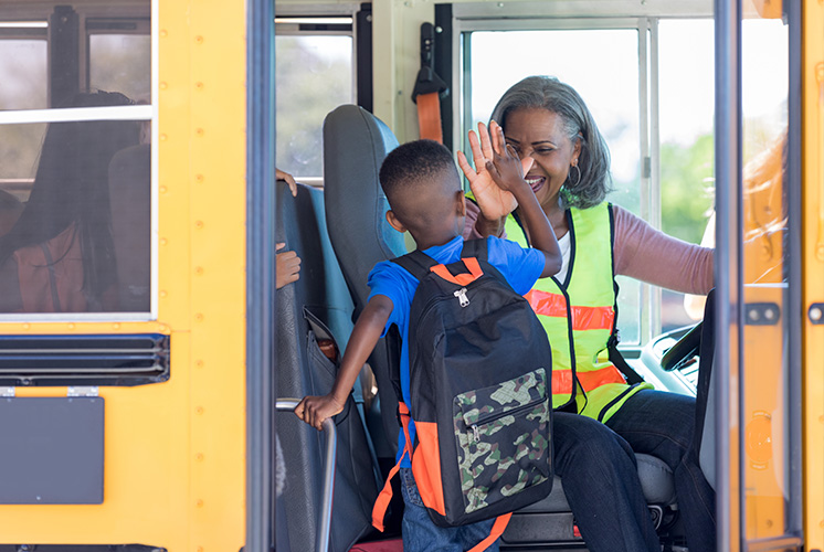 Niño subiendo al autobús y saludado por el conductor del autobús