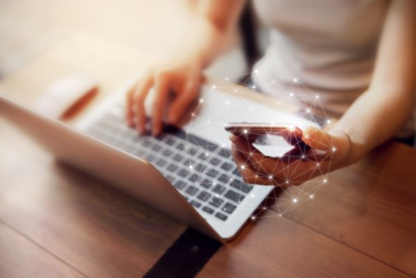 Woman working with her laptop and her cell phone.