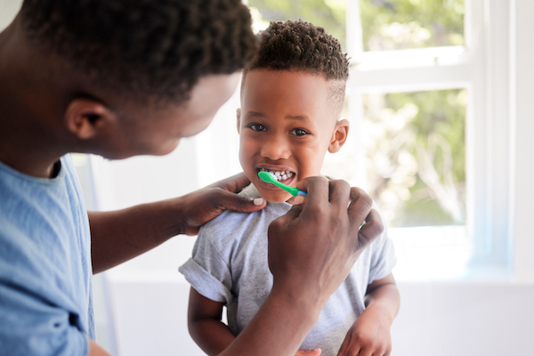 Padre ayudando a su hijo para el cepillado de dientes