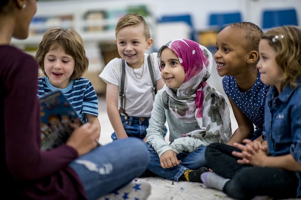 Niños de diversas etnias escuchando atentamente a su maestro.