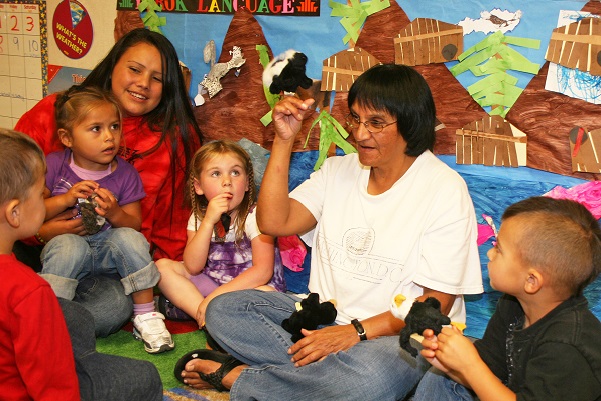 Mujer nativa americana hablando con niños en un aula sobre tradiciones culturales