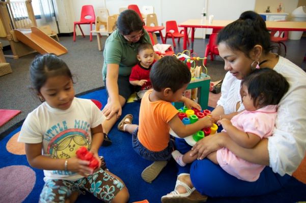 Maestros y niños pequeños sentados en un aula.