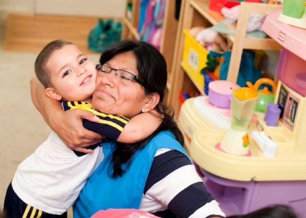 Teacher hugging a child in the classroom.