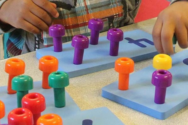 Child setting pegs in a math board.