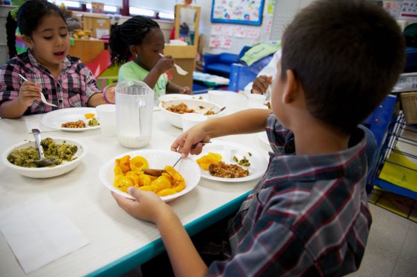 Children eating family style meals in a classroom.