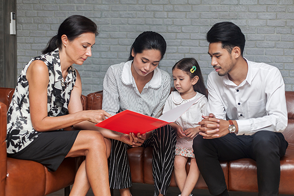 Social worker showing to a family information contained in a red binder.