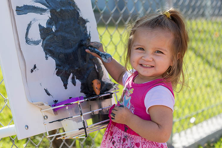 a girl outside is painting on paper on an easel