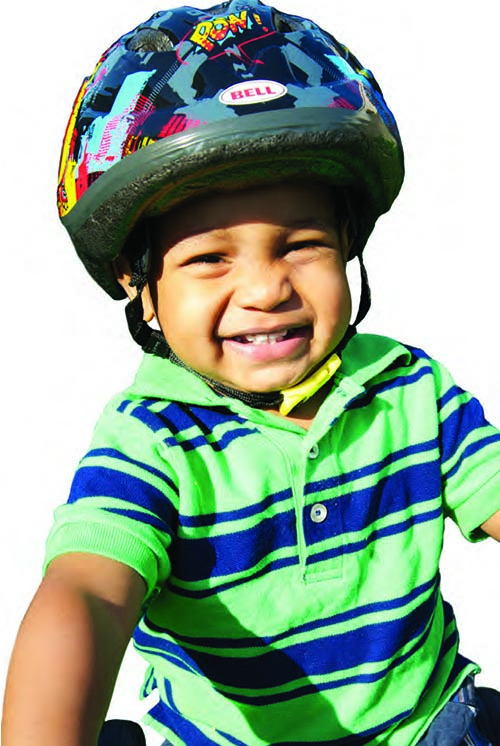 A smiling boy is wearing a bike helmet