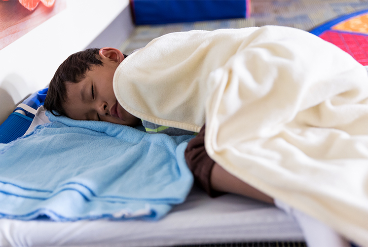 A boy naps under a blanket