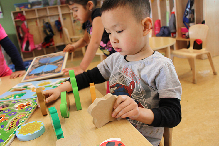 A boy plays with wooden shapes