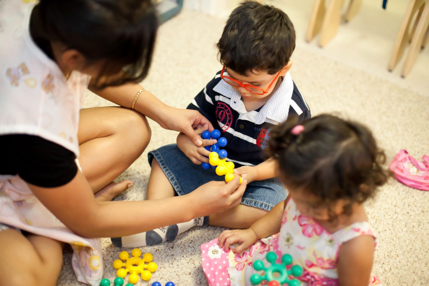 A un niño pequeño con gafas le muestran cómo usar piezas de rompecabezas entrelazadas.