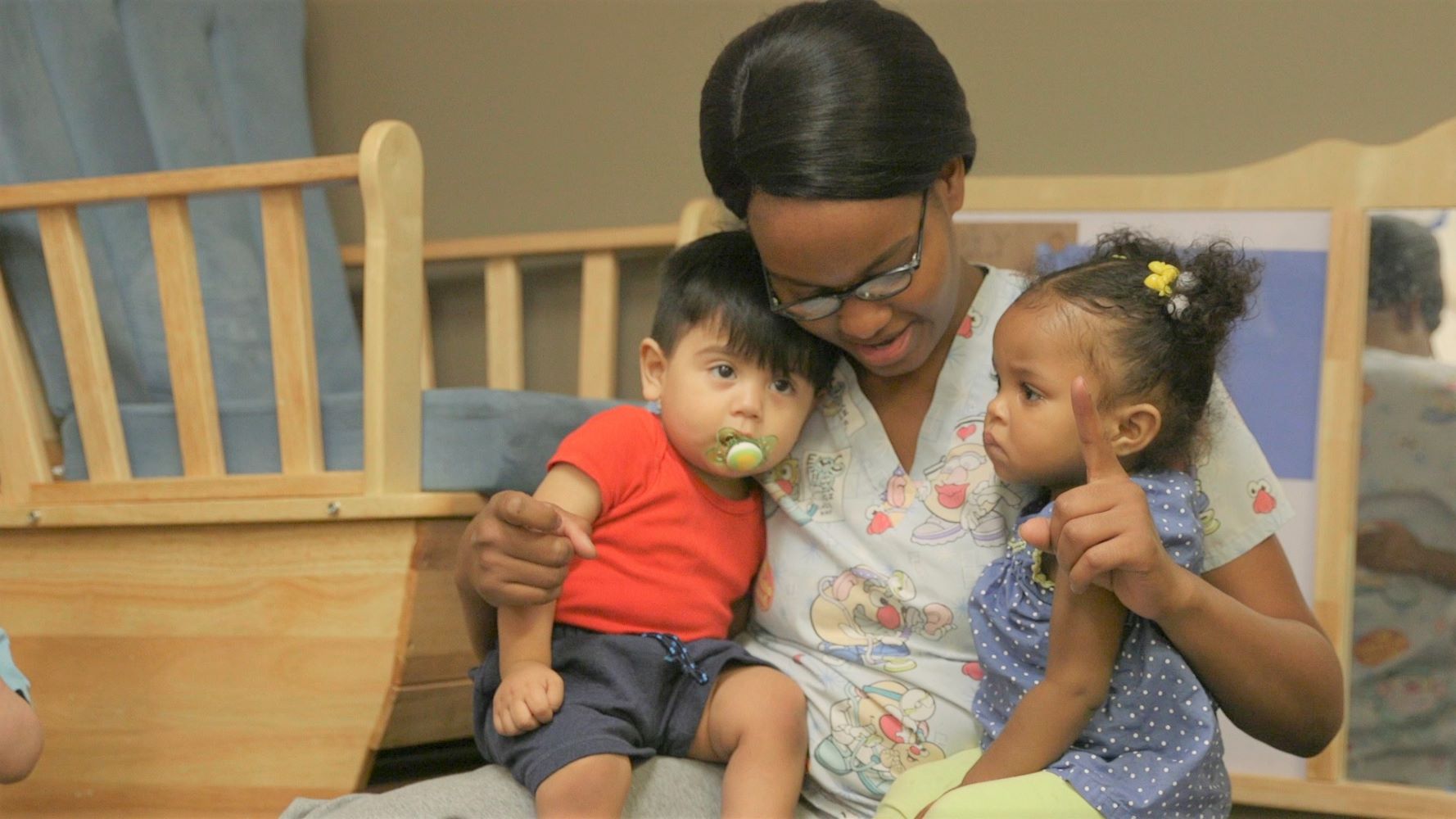 Caregiver interacting with two children on each lap.