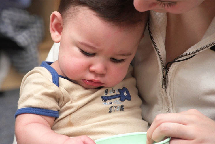 cuidadora sosteniendo a un niño pequeño con un juguete