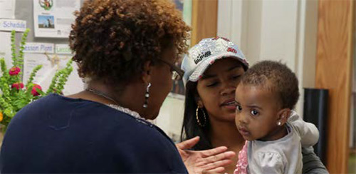 A teacher talks with a mother and young child