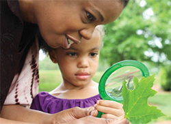 mujer y niño con lupa mirando plantas