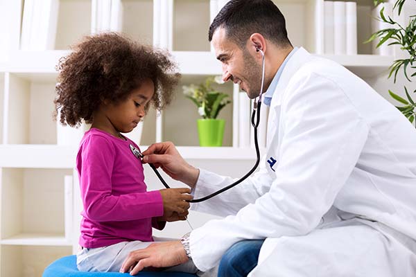 Doctor listening to a female child's heart in a doctor's office setting