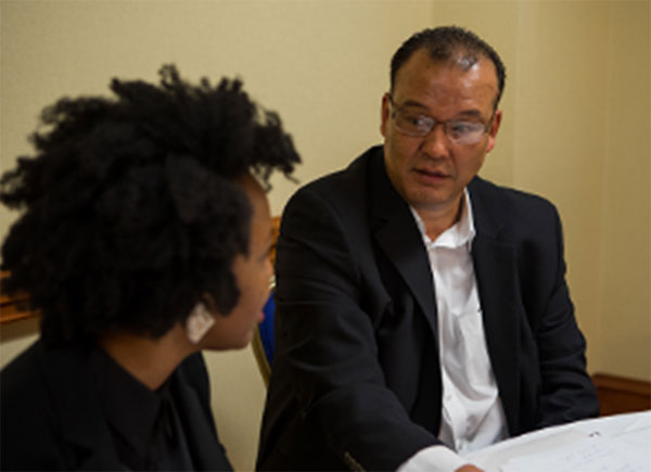 A man and a woman in business attire talking at a conference table