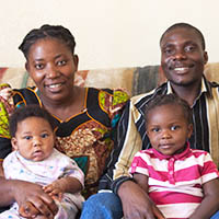 a smiling family sits on the couch together