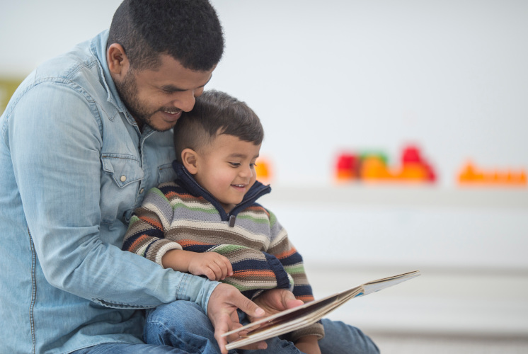 A father is reading to his son on father's day in their home