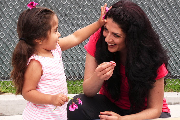 A girl puts flowers in her and a caretaker's hair