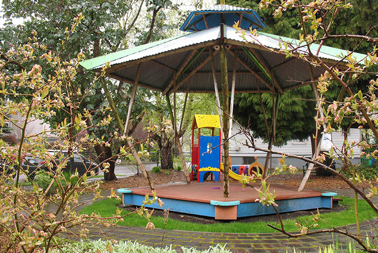 an outdoor space with paths encircling a gazebo with play equipment inside