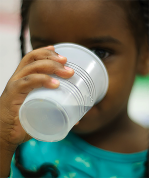 Young girl drinking water out of a plastic cup