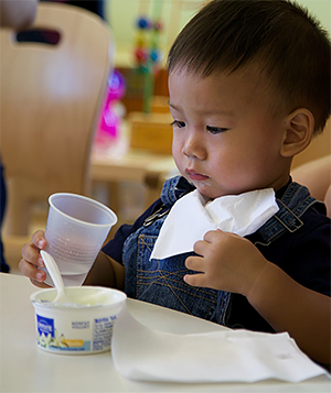 Little boy eating yogurt and drinking water