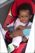 Young girl being securely buckled into her car seat.