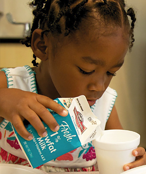 child pouring milk into cup