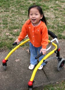 Smiling young girl in a park setting using a walker.