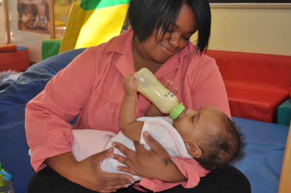 A mother bottle feeding her infant child.