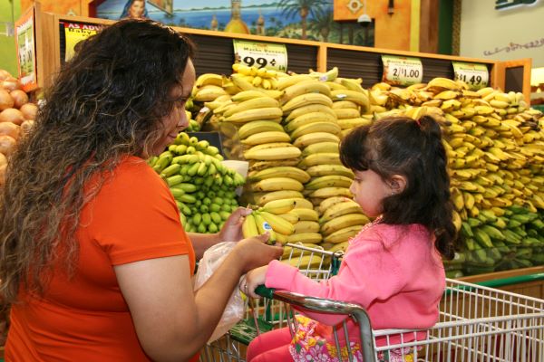 Mother and child buying produce in a supermarket.