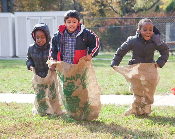 Three boys racing in potato sacks.