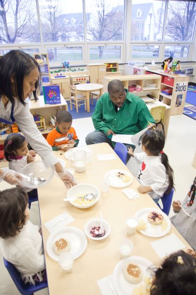 Children sitting at a table being served food.