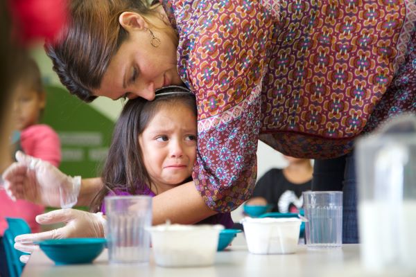 Un niño preocupado es abrazado por un miembro del personal del servicio de alimentos.