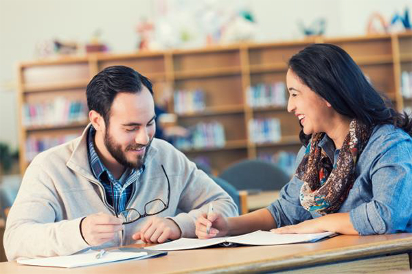 Two teachers reading a notebook