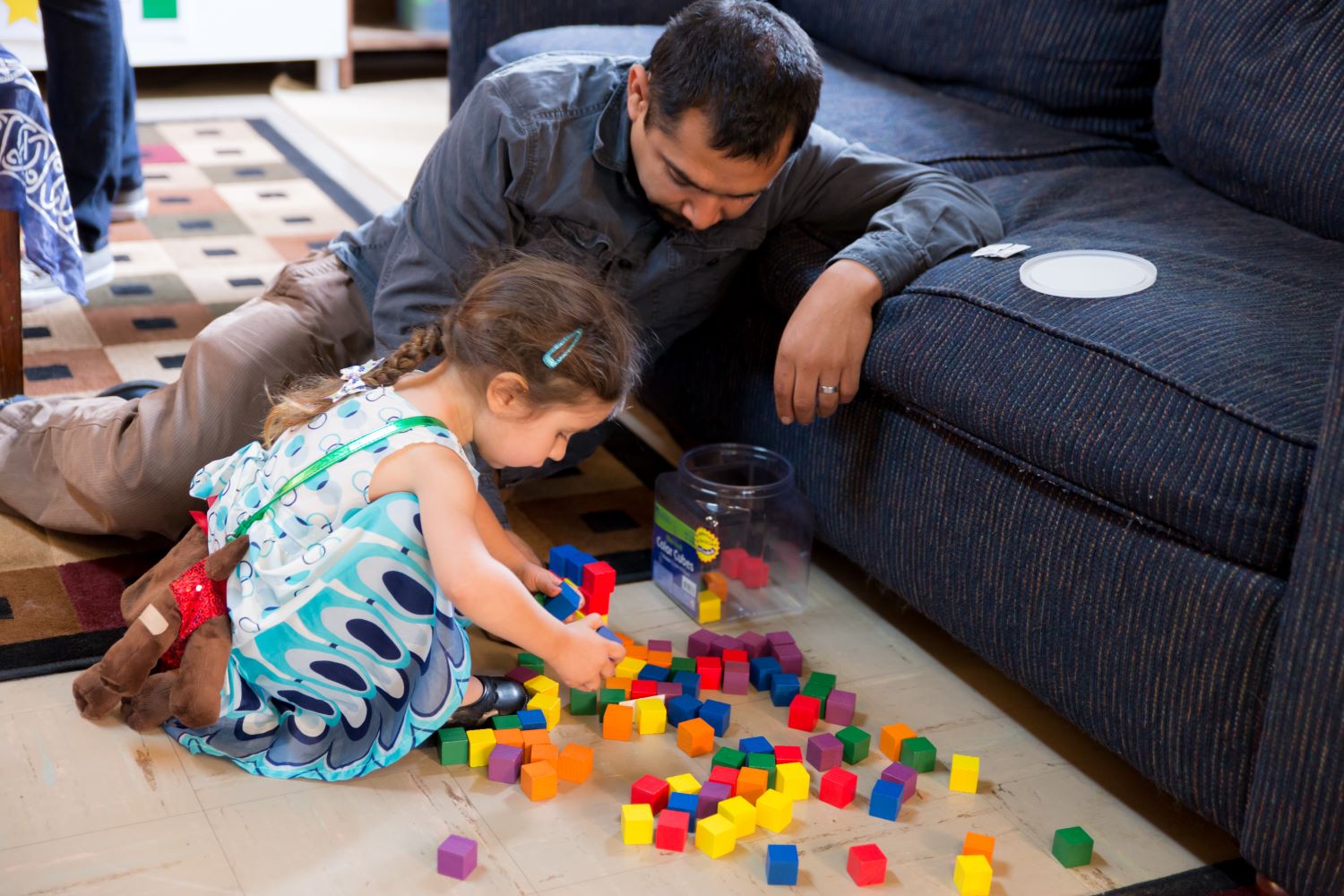 Padre e hija en el suelo jugando con bloques.