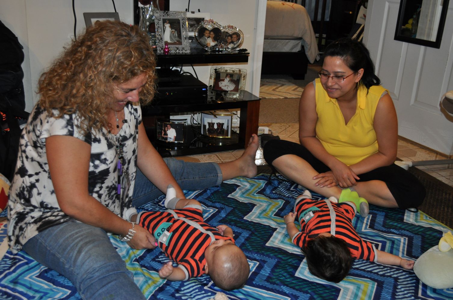 Home visitor and mother placing infants on floor.