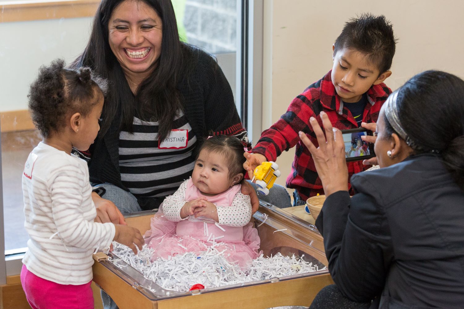 Teachers and small children entertaining an infant.