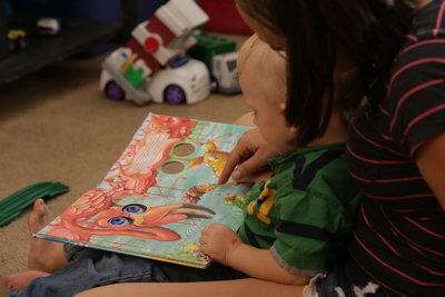 Adulto ayudando al niño a leer un libro.